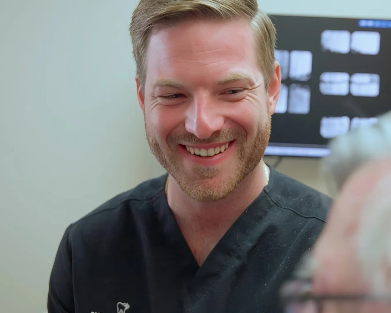 Dr. Dillon Hernandez sharing a genuine laugh with a patient in a Cardinal Point Dental treatment room, at a Jacksonville, FL dental office offering exams and implant treatment