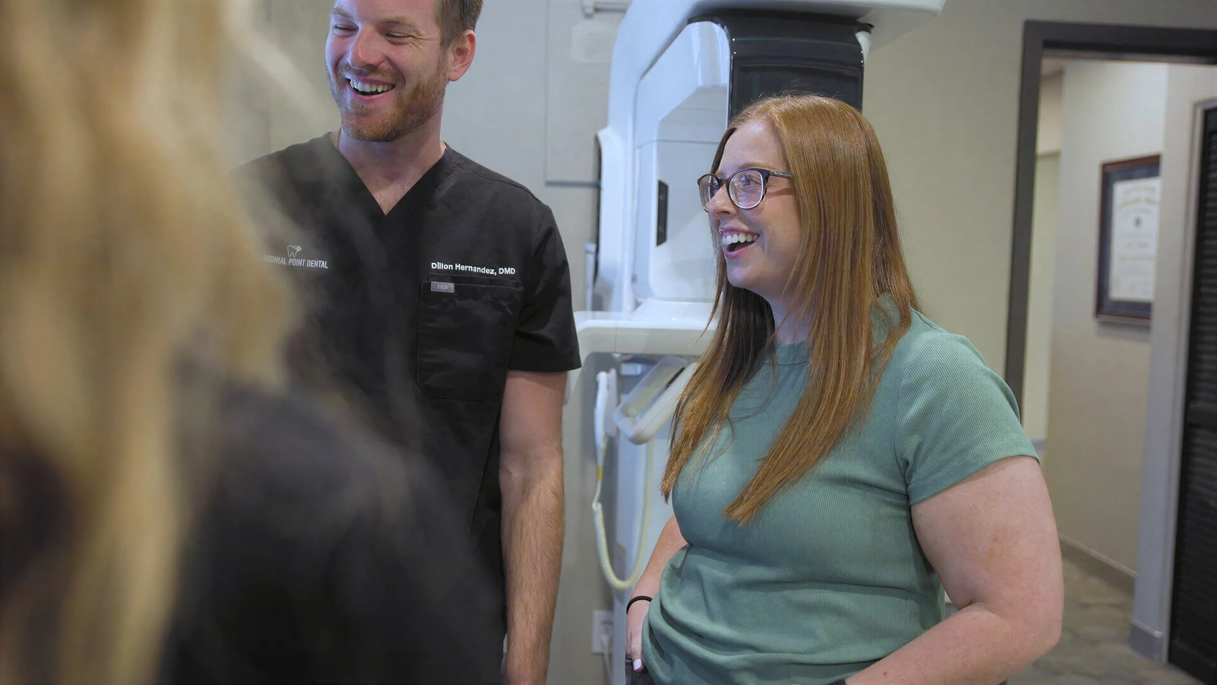 Dr. Dillon Hernandez laughing with a team member beside the X-ray scanner at Cardinal Point Dental — tooth extractions in Jacksonville, FL