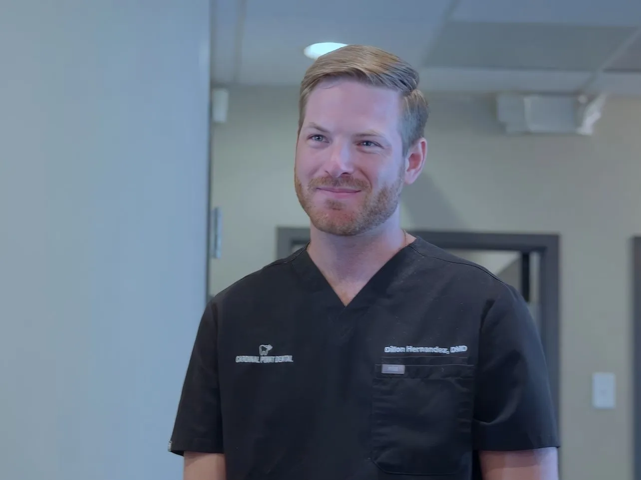 Dr. Dillon Hernandez smiling in a hallway at Cardinal Point Dental, Jacksonville, FL (tooth-colored fillings)