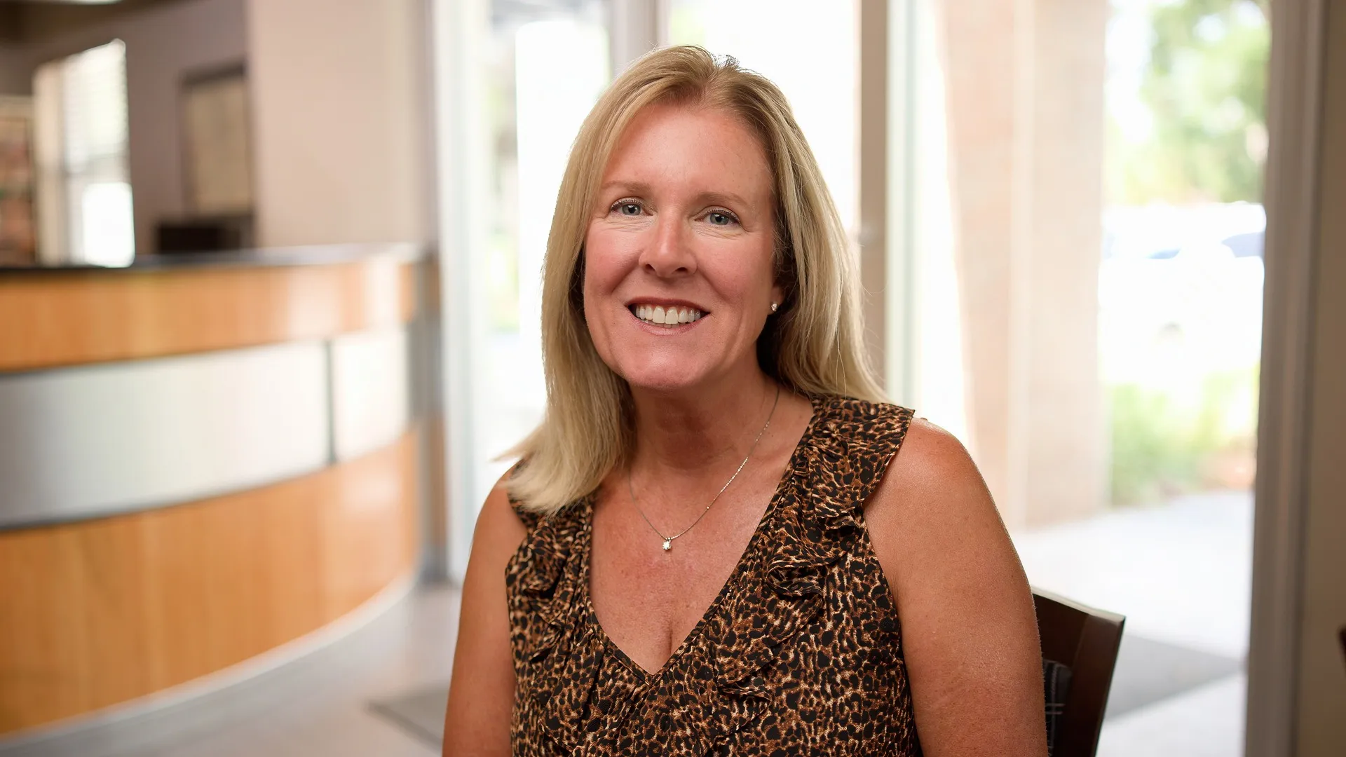 Laurie, a Cardinal Point Dental patient, smiling to camera in the office lobby, Jacksonville, FL (teeth cleanings and exams)