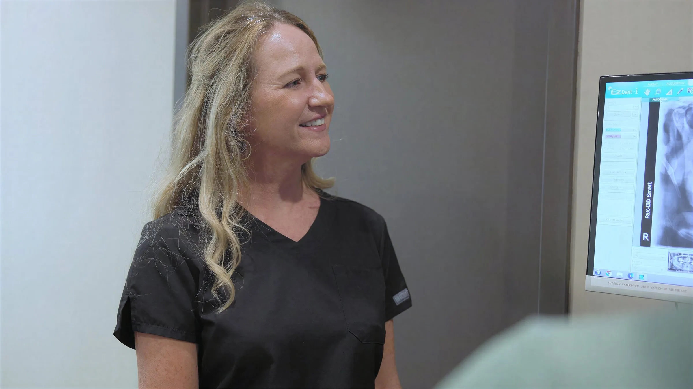 A smiling Cardinal Point Dental team member beside a treatment-room monitor in Jacksonville, FL (night guards)